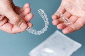 un dentista muestra ortodoncia invisible, una en cada mano